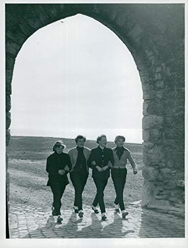 Реколта снимка на няколко приятели, които вървят ръка за ръка през една от арките на стената в Висбю